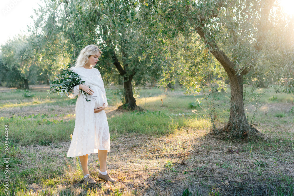 Pregnant woman standing in olive grove Pregnant woman standing in olive grove
