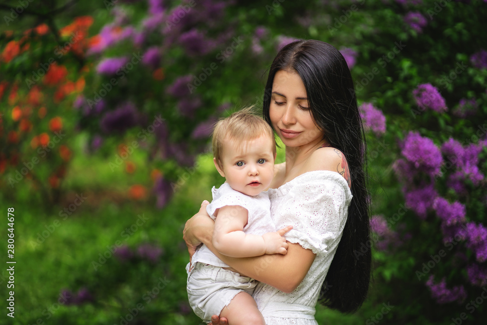 Mother holds the child and looks at her with tenderness. The child looks into the frame Mother holds the child and looks at her with tenderness. The child looks into the frame