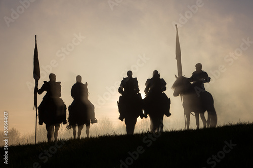 A group of medieval knights silhouetted against the sunset. photo