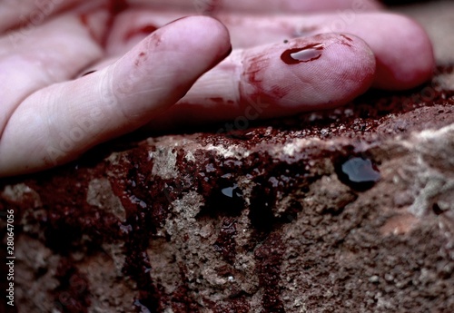 Human hand lies limp on the ground in a pool of blood. Crime, murder.