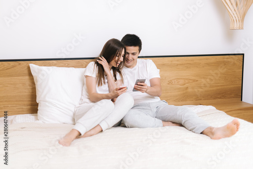 Smiling man showing photo on mobile phone to girl