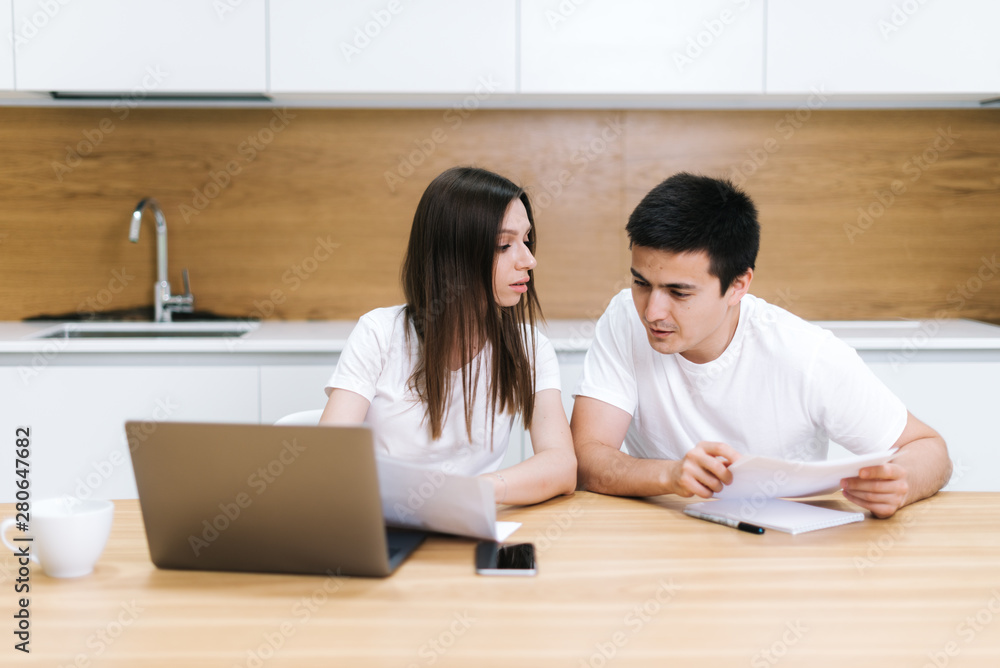 Couple is sitting at kitchen table, use laptop and taking care of utility bills Couple is sitting at kitchen table, use laptop and taking care of utility bills