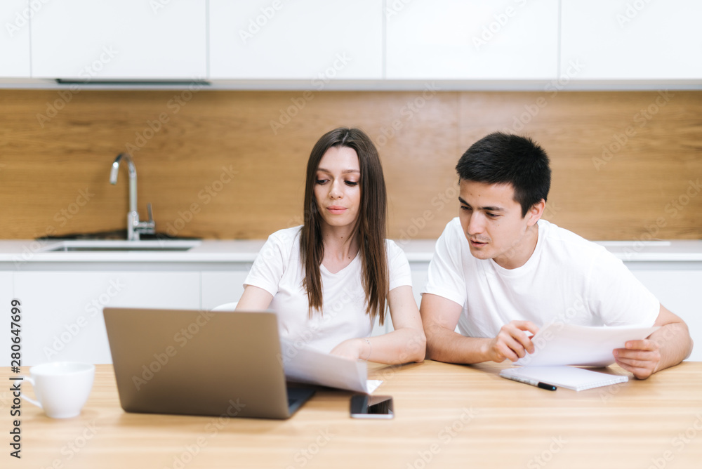 Young couple managing finances, reviewing their bank accounts using laptop Young couple managing finances, reviewing their bank accounts using laptop