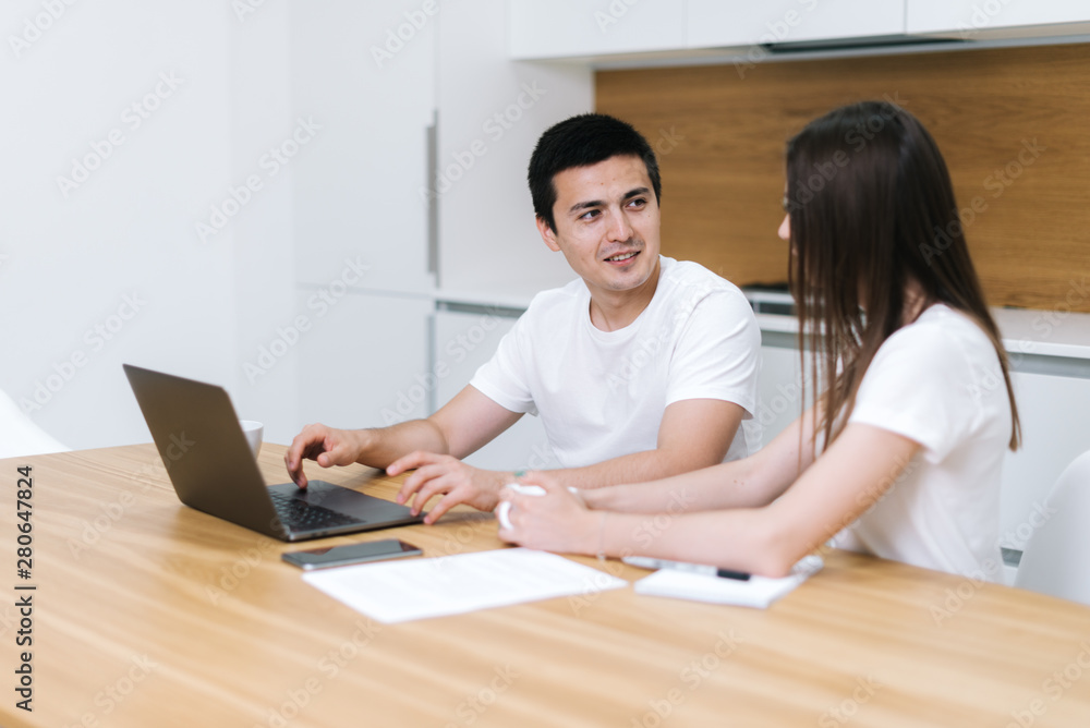 Young couple using laptop at home. Happy man and woman looking at each other Young couple using laptop at home. Happy man and woman looking at each other