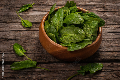 Spinach in a wooden plate on a wooden background