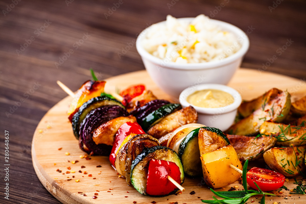 Kebabs - grilled meat with french fries and vegetables wooden background Kebabs - grilled meat with french fries and vegetables wooden background