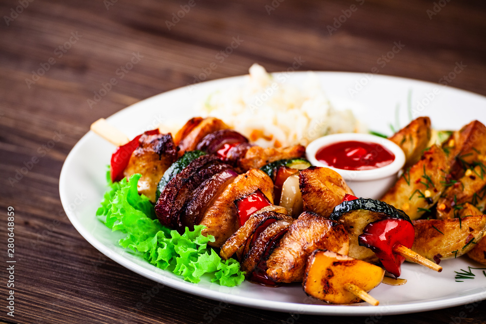 Kebabs - grilled meat with french fries and vegetables wooden background