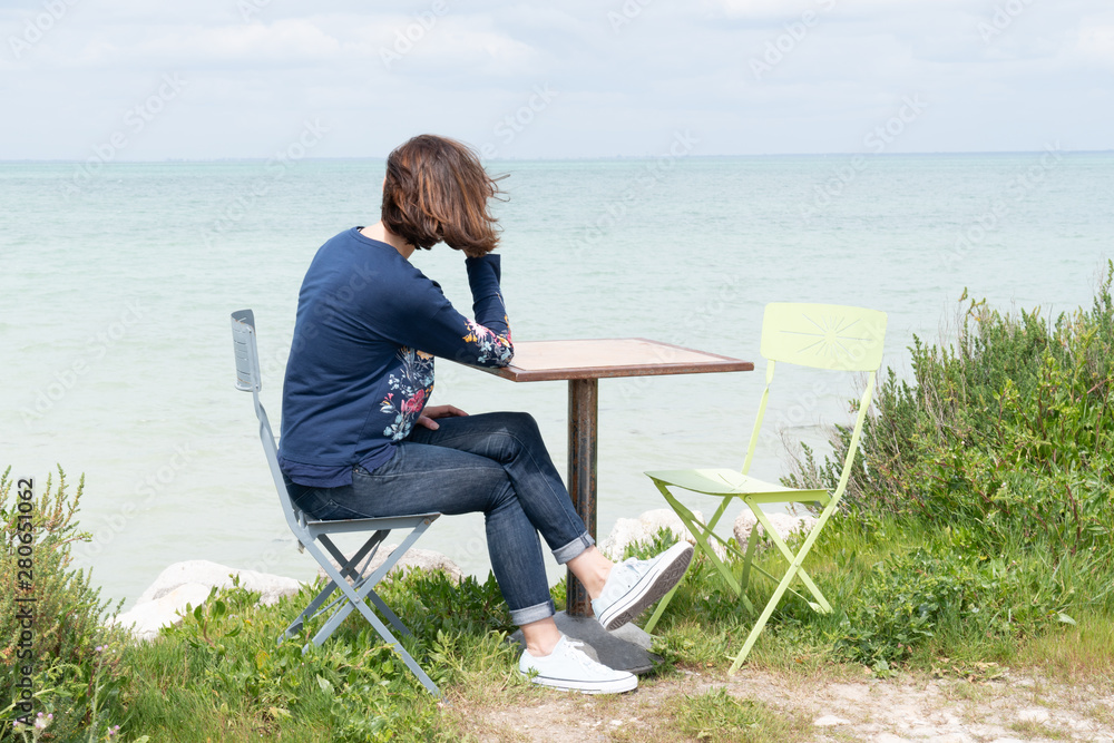 Woman alone in table on beach coast in Island Ile de Re in France