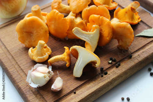 fresh chanterelles and ingredients for cooking on wooden board