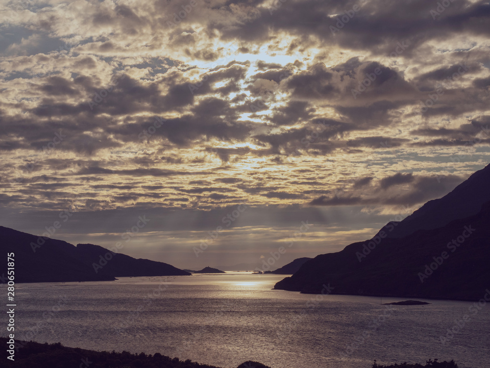 Beautiful, dramatic sunset sky over Killary fjord, county Galway. Sun rays shine through the clouds. Calm and peaceful mood. Toned.