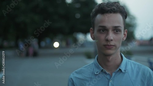 Camera turning around a serious young handsome man on the embankment in the evening, Slow motion