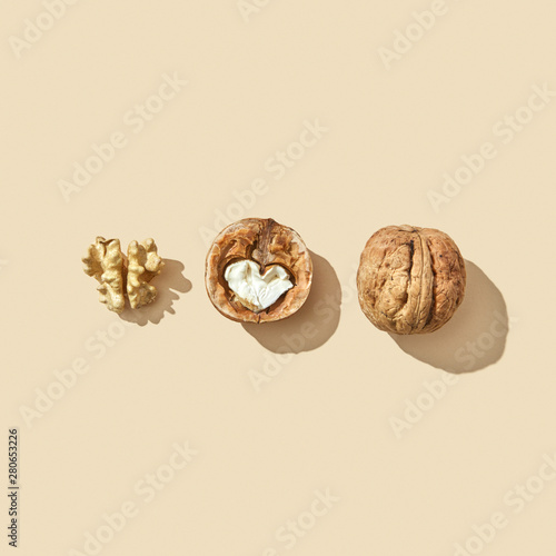 Set of whole, halved and middle of a walnut on a beige background with shadow and copy space. Healthy food. Flat lay photo