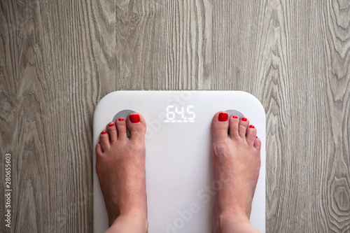 Wallpaper Mural Woman stands on white modern electronic scales, which show 64.5 kg. Only feet are visible. Scales stand on gray wooden floor. Space for text. Healthy lifestyle, diet, weight loss concept. Horizontal. Torontodigital.ca