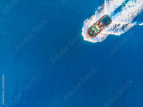 Tugboat sails to meet liner or cargo ship in port. Top view of blue ocean photo