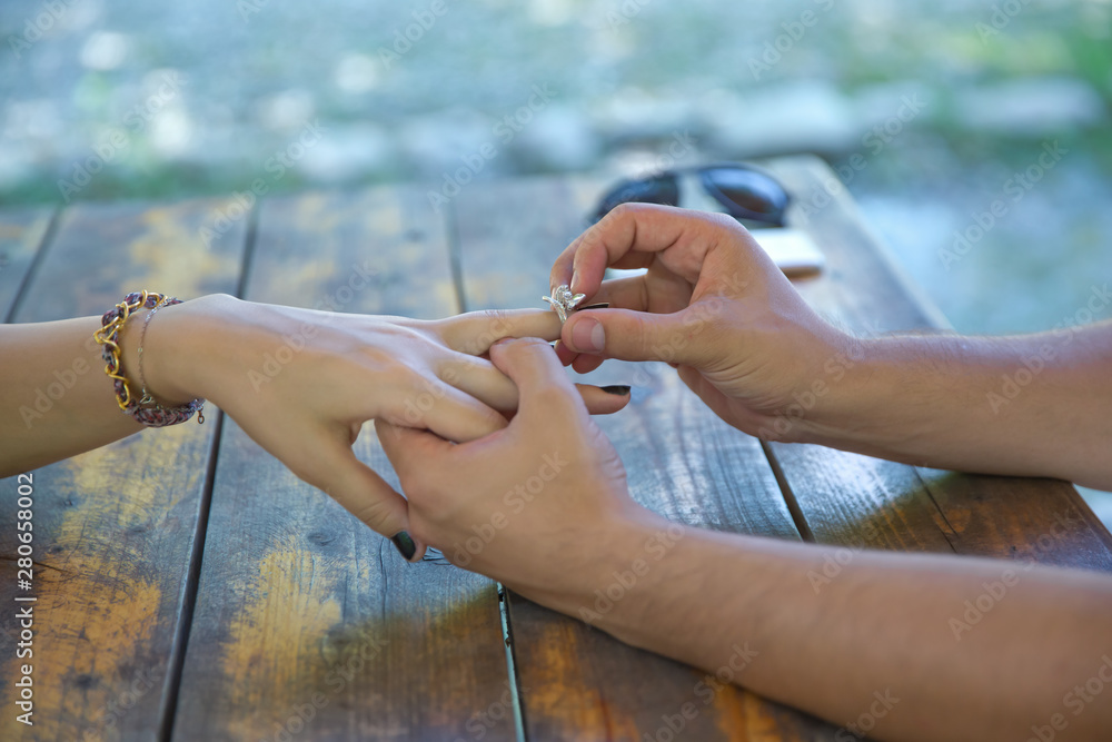 The man is giving a ring to his girlfriend and wearing in on her finger.  Young woman caught because her boyfriend gives an engagement ring at  breakfast . Stock-foto | Adobe Stock