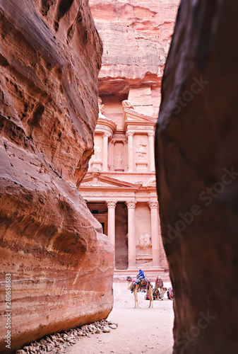 Peering through the rock walls at bedouin guides sitting with their camels in front of the Treasury at Petra.