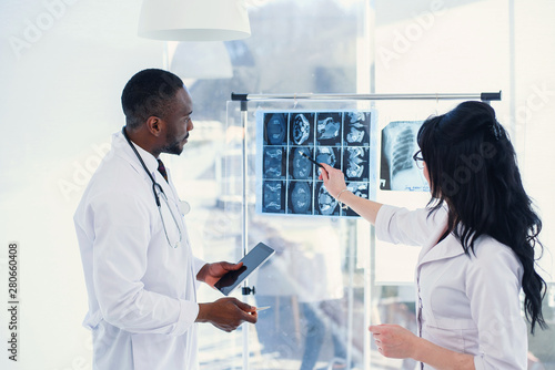 Two doctors look at an x-ray and discuss the problem. Medical technicians pointing at MRI x-ray of patient. Radiologist checking x-ray. Medical and radiology concept. photo