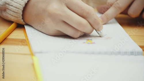 Hand of child drawing and erasing a picture in her sketch pad.