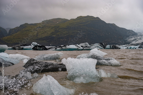 The Solheimajokull Glacier in Iceland showing icebergs and calved ice in the lagoon as ice calves and melts together with the erosion caused by the receding glacier photo