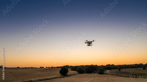 Aerial view of drone flying with digital camera over a field with sunset