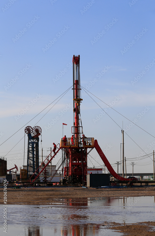 The pumping unit is operating in the oil field in the evening, silhouetted against the sky