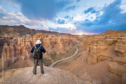 Tourist with a backpack looking on sunset in Charyn Canyon, Almaty Region, Kazakhstan