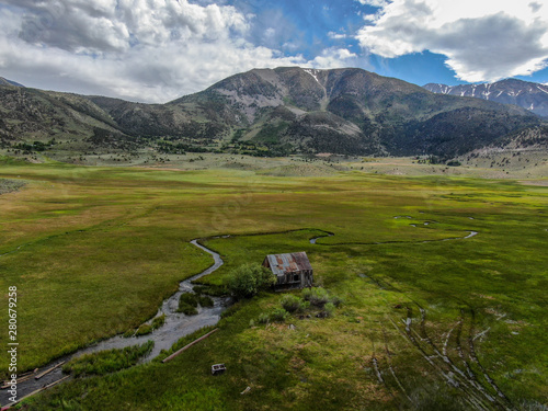 Aerial view of abandoned little small wooden house barn next small river in the green valley of a mountain, Aspen Spring, Mono County, California, USA.  photo