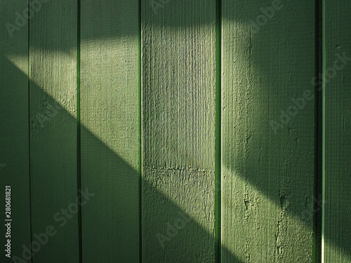 The sunlight hits the green wooden fence. A beautiful ray of sun in the form of an arrow hit the room