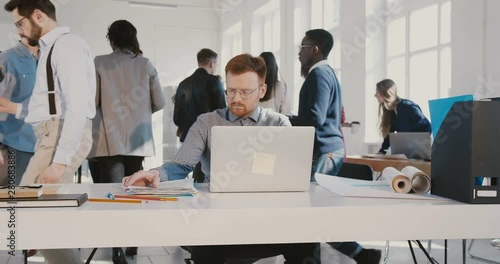 Stressed young office worker man throwing papers in the air, walking away from busy modern office table RED EPIC.