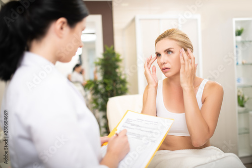 Woman explaining her needs to a beauty doctor. photo