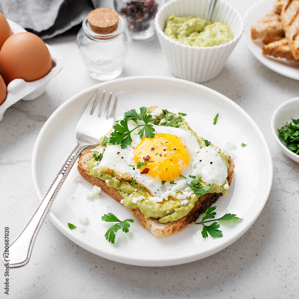 Toast with avocado puree and fried egg, healthy breakfast. 