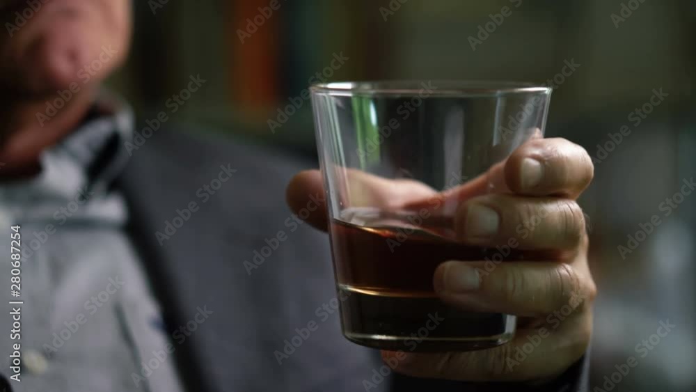 Old Bald Man in Suit Swirling Whiskey in Glass - Dramatic Lighting Old Bald Man in Suit Swirling Whiskey in Glass - Dramatic Lighting