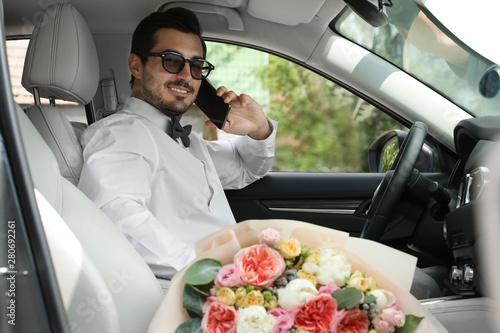 Young handsome man with beautiful flower bouquet sitting in car