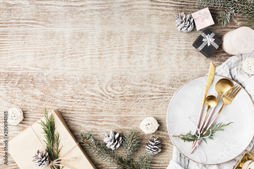 Festive wooden table setting with winter decorations, cutlery, candles and gifts. Top view, flat lay. The concept of a Christmas family dinner. photo