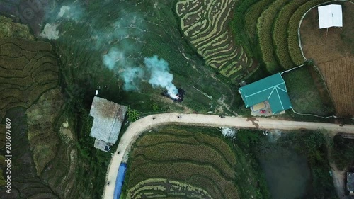 aerial high angle shot above Moang Hoa Valley. Smoke rising from the burning rice plants and people riding motorcycles on the road photo