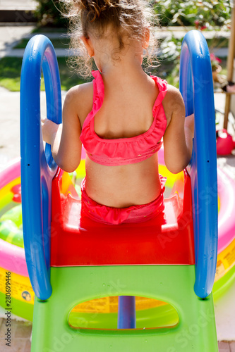 Children playing in inflatable chute. Happy little girl playing on hot summer day.