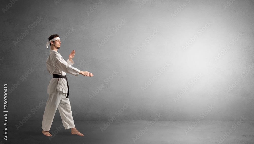 Small karate man fighting in an empty grey copy space Small karate man fighting in an empty grey copy space