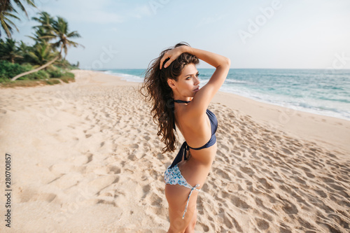 Closeup face of young woman with eyes closed enjoying breeze at beach. Portrait of carefree girl relaxing at sea. Beautiful smiling woman enjoying at beach the sun