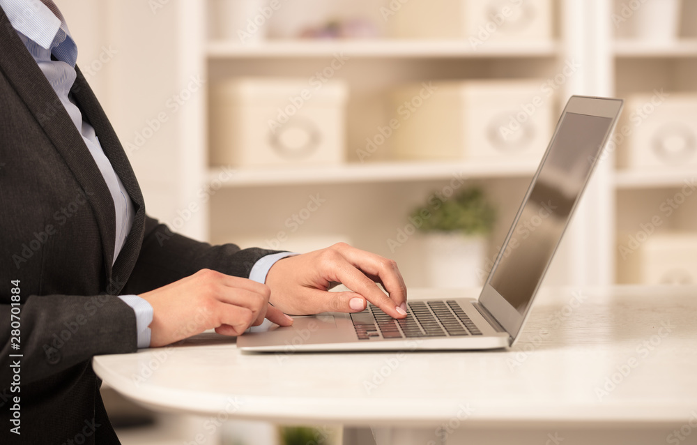 Business woman below chest working on her laptop in a cozy environment Business woman below chest working on her laptop in a cozy environment
