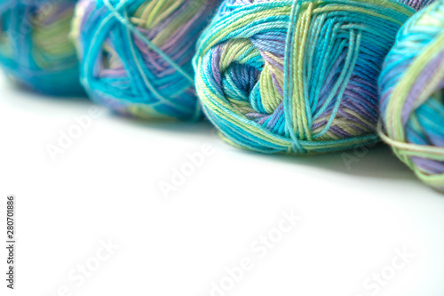 Skeins of multi-colored gradient yarn for knitting children's clothes on white background. Gentle multicolor yarn of blue, green, violet color. For yarn, fabric stores, for design of banners, flyers