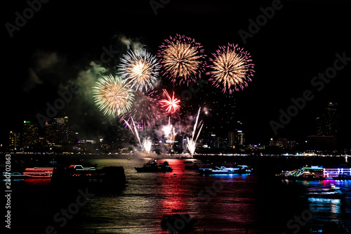 Fireworks over cityscape by the beach and sea surrounding with hotels, restaurant, and service boats and cruises during blue twilight time for celebrating New Year eve and special occasion on.