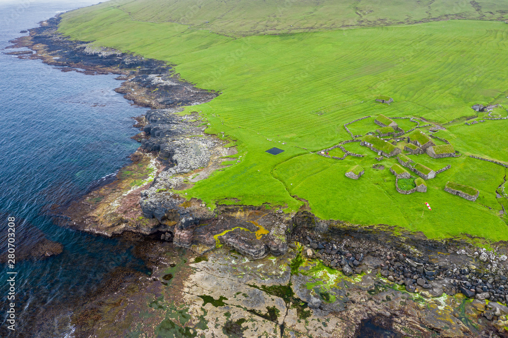 Aerial view of fishing village in Koltur island. Faroe Islands. Green roof houses. Photo made by drone from above. Nordic natural landscape.