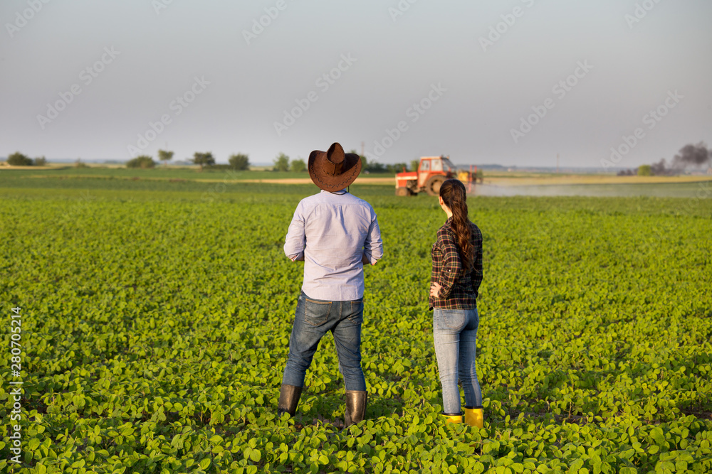Farmers in front of tractor in field