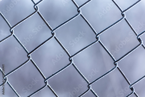 Close up view of Frozen metal fence frost covered in cloudy winter day. Soft focus