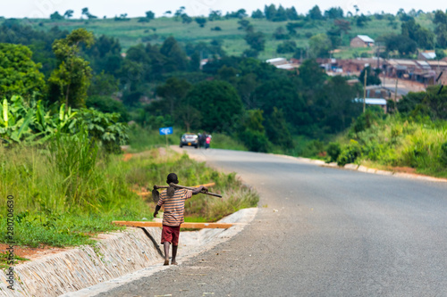 A boy with a hoe is walking down a street in Uganda photo