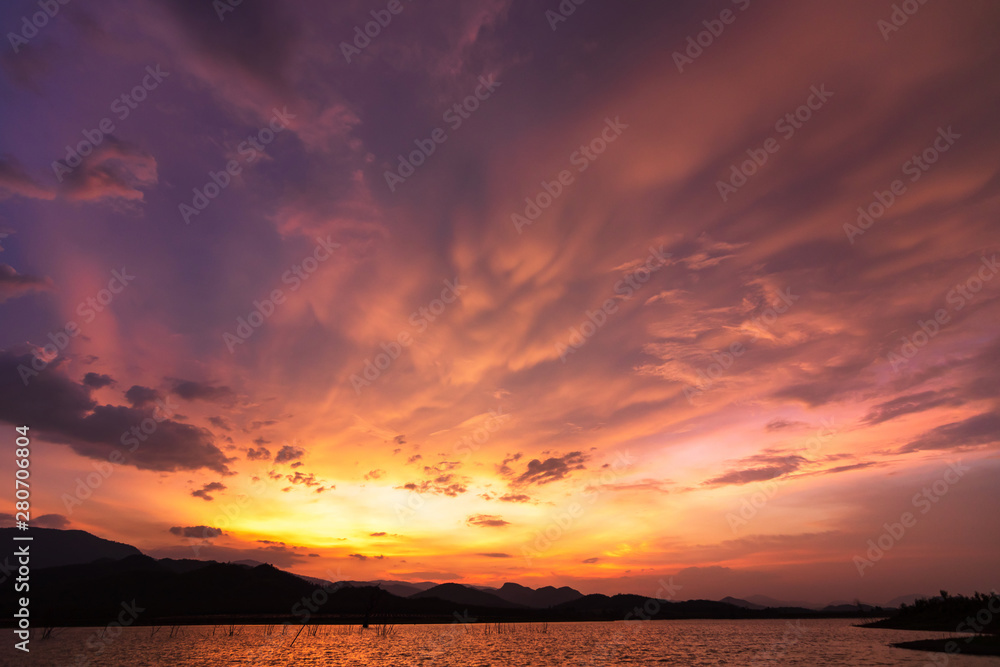 Dramatic sunset sky above a surface of lake, natural background.