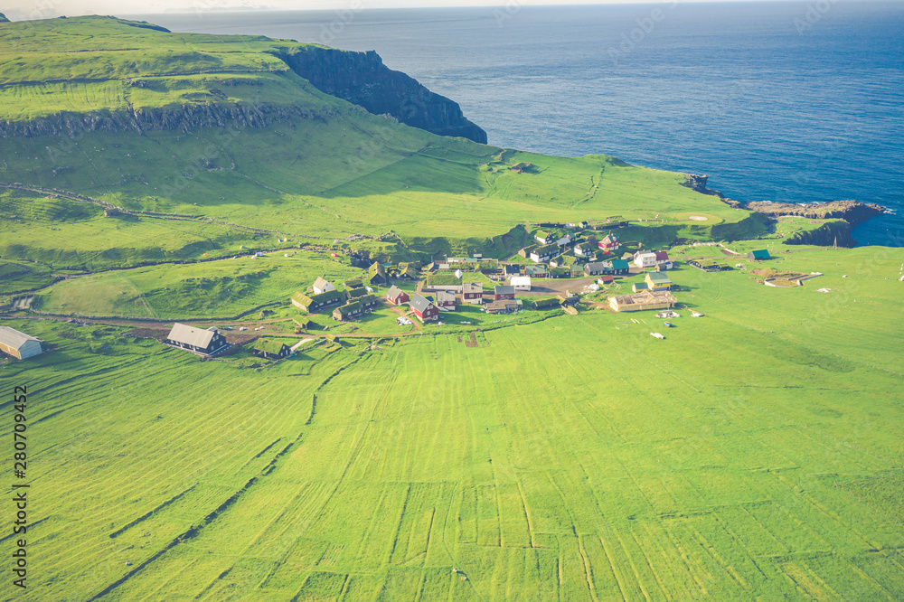 Aerial view of village at Mykines island in Faroe Islands, North Atlantic Ocean. Photo made by drone from above. Nordic natural landscape.