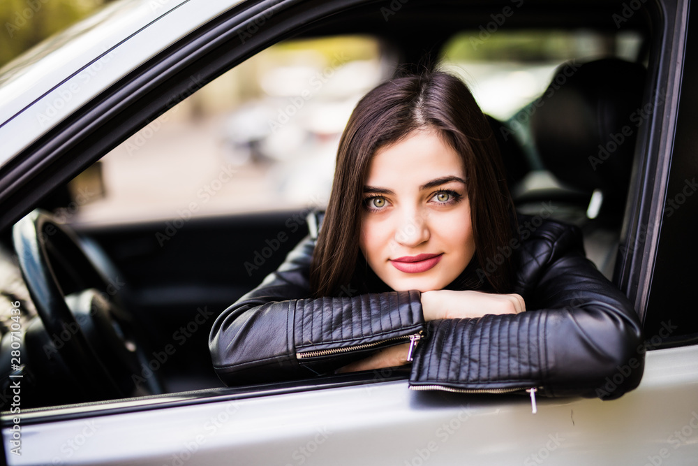 Beautiful girl in jacket is smiling while driving a car