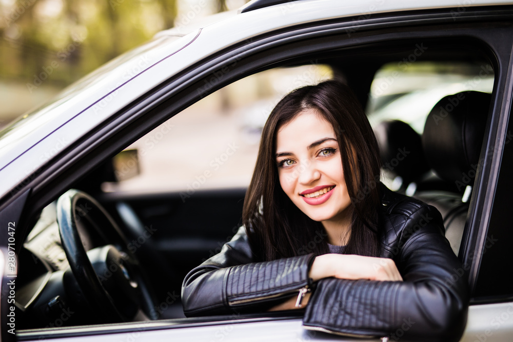 Portrait of young woman sitting in the car looking out the window, leaning on the arm