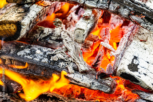 Beautiful bonfire from burning oak barbecue. Fire over burning coals. Cooking coals for cooking barbecue on grill. Selective focus. Blurred background.. Dark charred wood and red-hot coals.